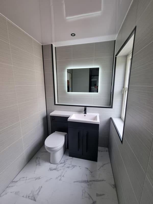 Bathroom with dark vanity and LED mirror