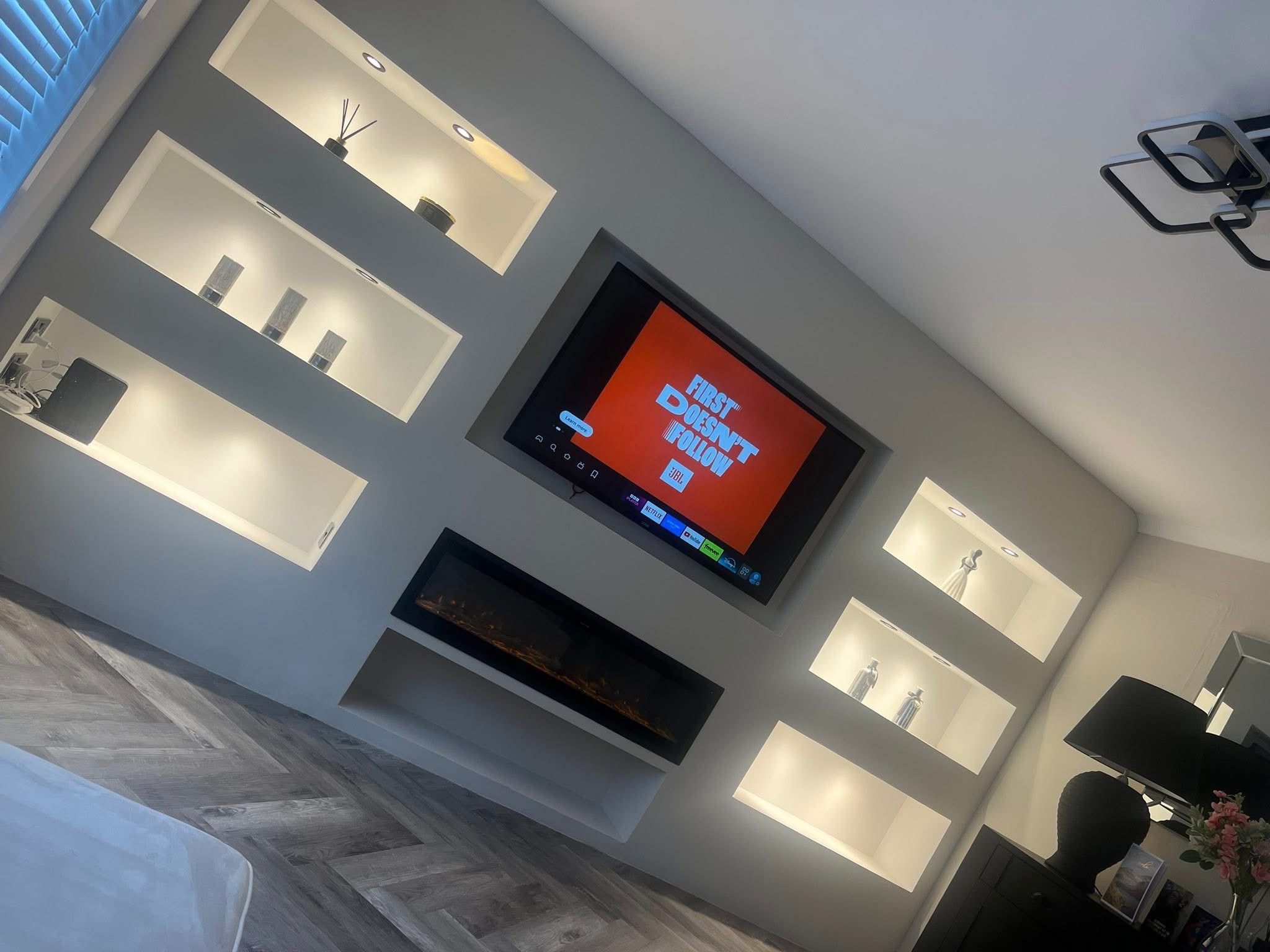 Grey media wall with lit niches and recessed fireplace